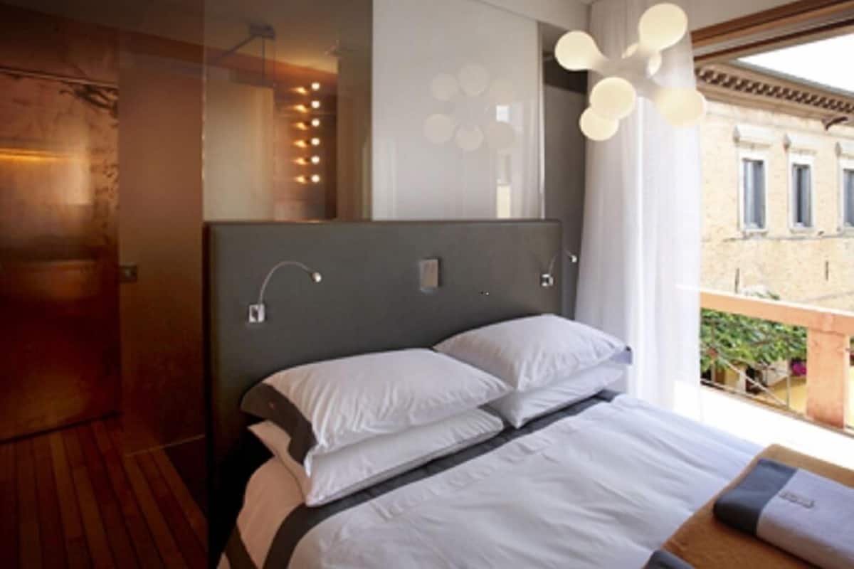 Ein modernes Hotelzimmer mit einem großen Bett, Holzboden, einem Balkon mit Blick und einem einzigartigen Wanddesign.
