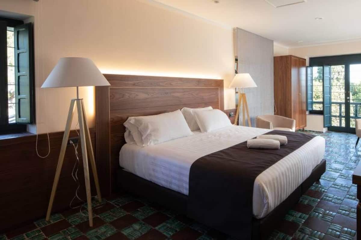 Ein Hotelzimmer mit einem großen Bett, zwei Nachttischlampen, einem Schreibtisch und einem Fernseher.