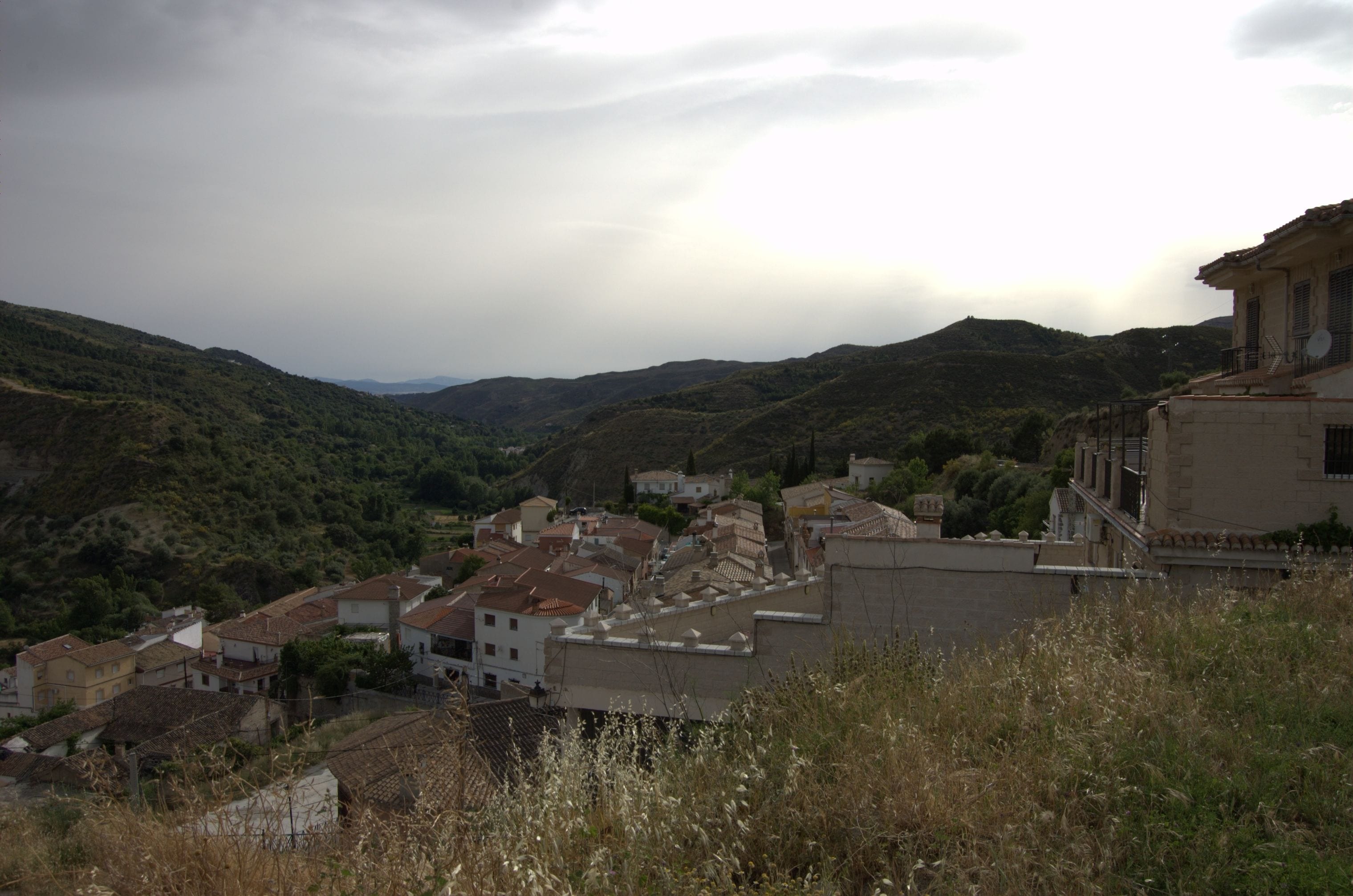 Un pueblo en la ladera con edificios tradicionales y campos en bancales.
