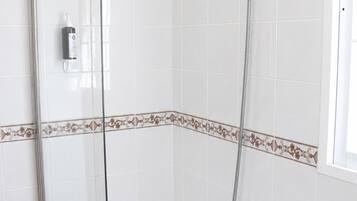 Een badkamer met een douchecabine van glas, een bad en een douchekop.