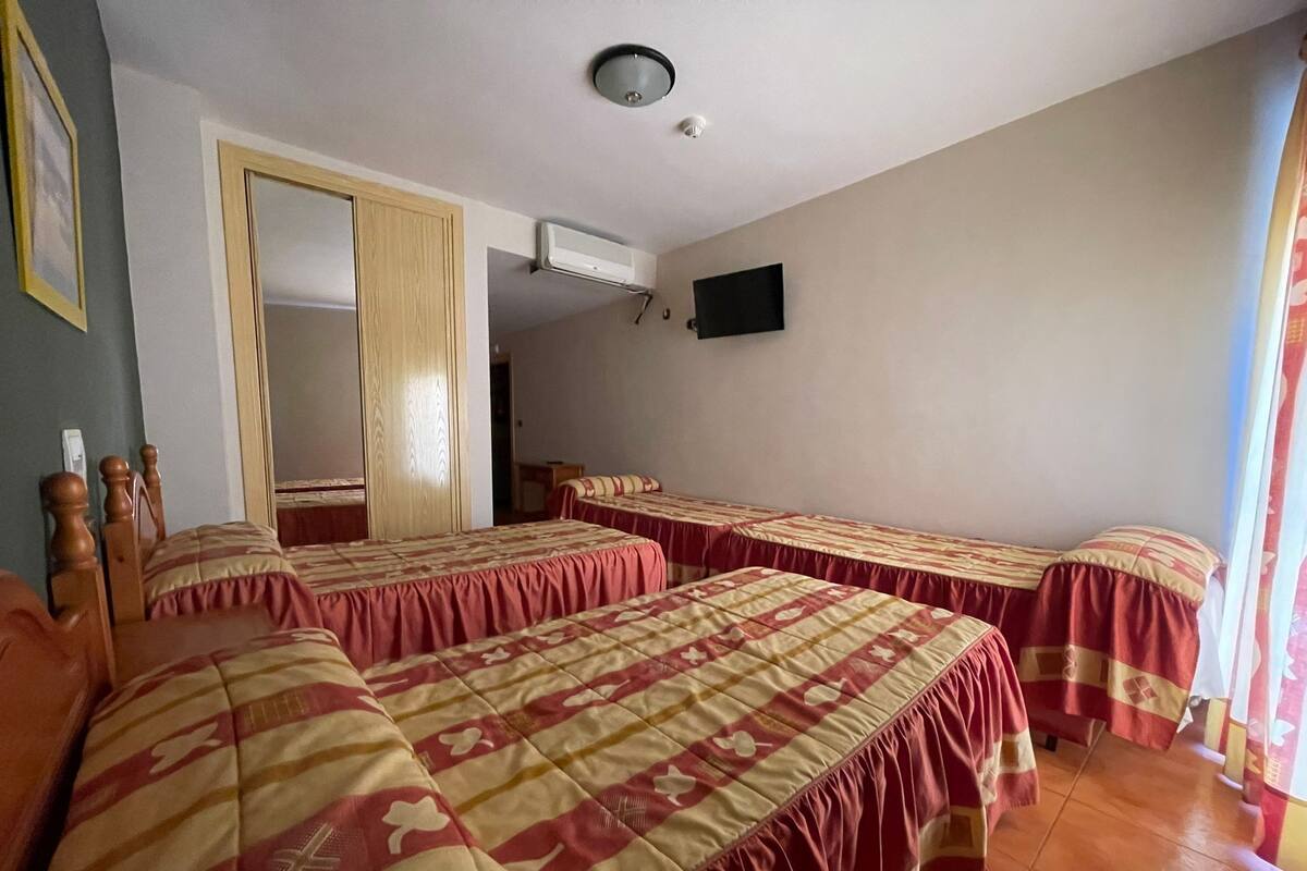Une chambre d’hôtel avec deux lits, une télévision et une armoire.