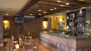 Un restaurant amb parets de maó, taules de fusta i una zona de bar amb un respatller de rajoles.