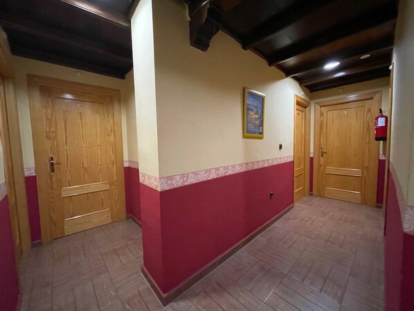 A hallway with wooden doors, a red and white wall, and a tiled floor.