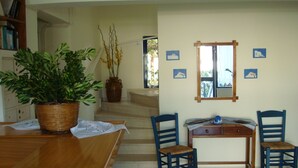 Uma área de refeições com uma mesa de madeira, cadeiras, um vaso de planta, um arranjo floral e um espelho na parede.
