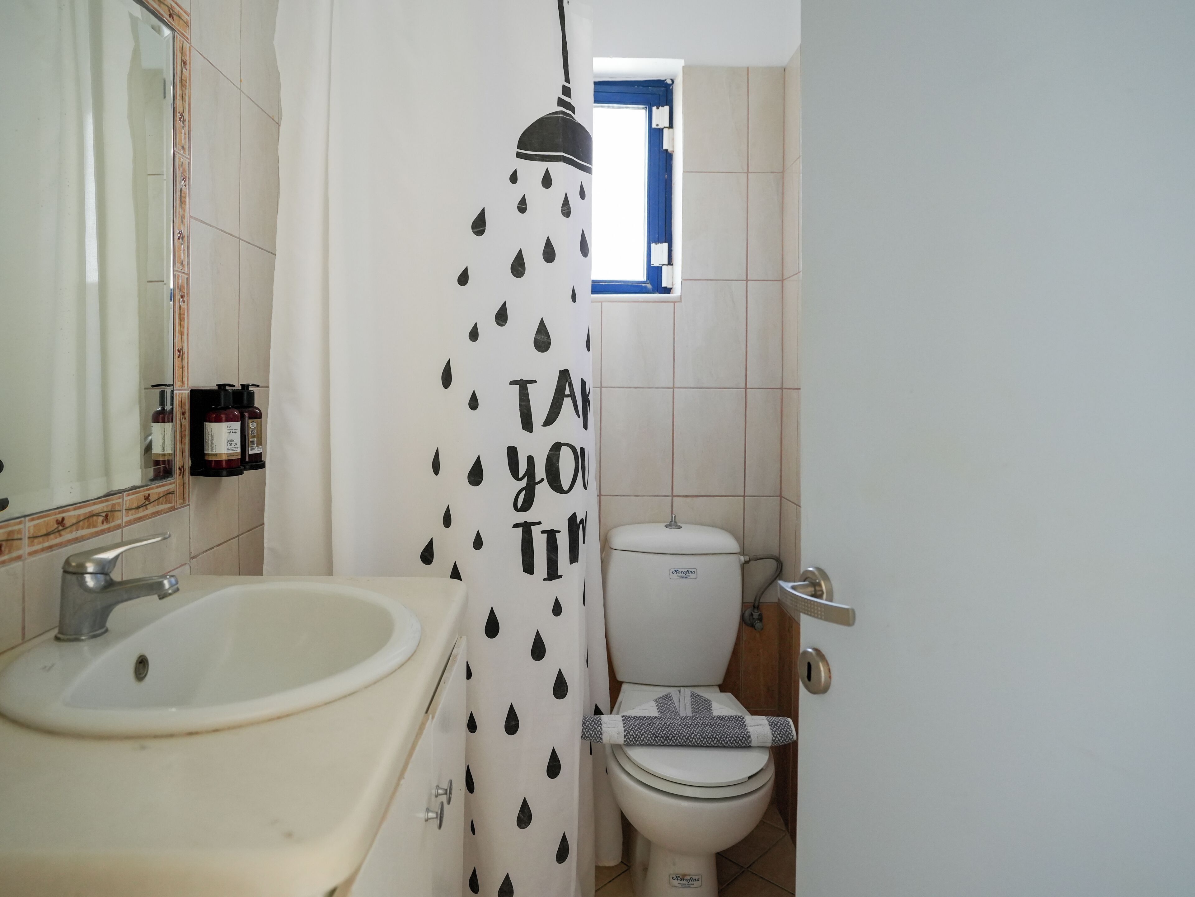 A bathroom with a sink, toilet, and shower curtain with a rain pattern.