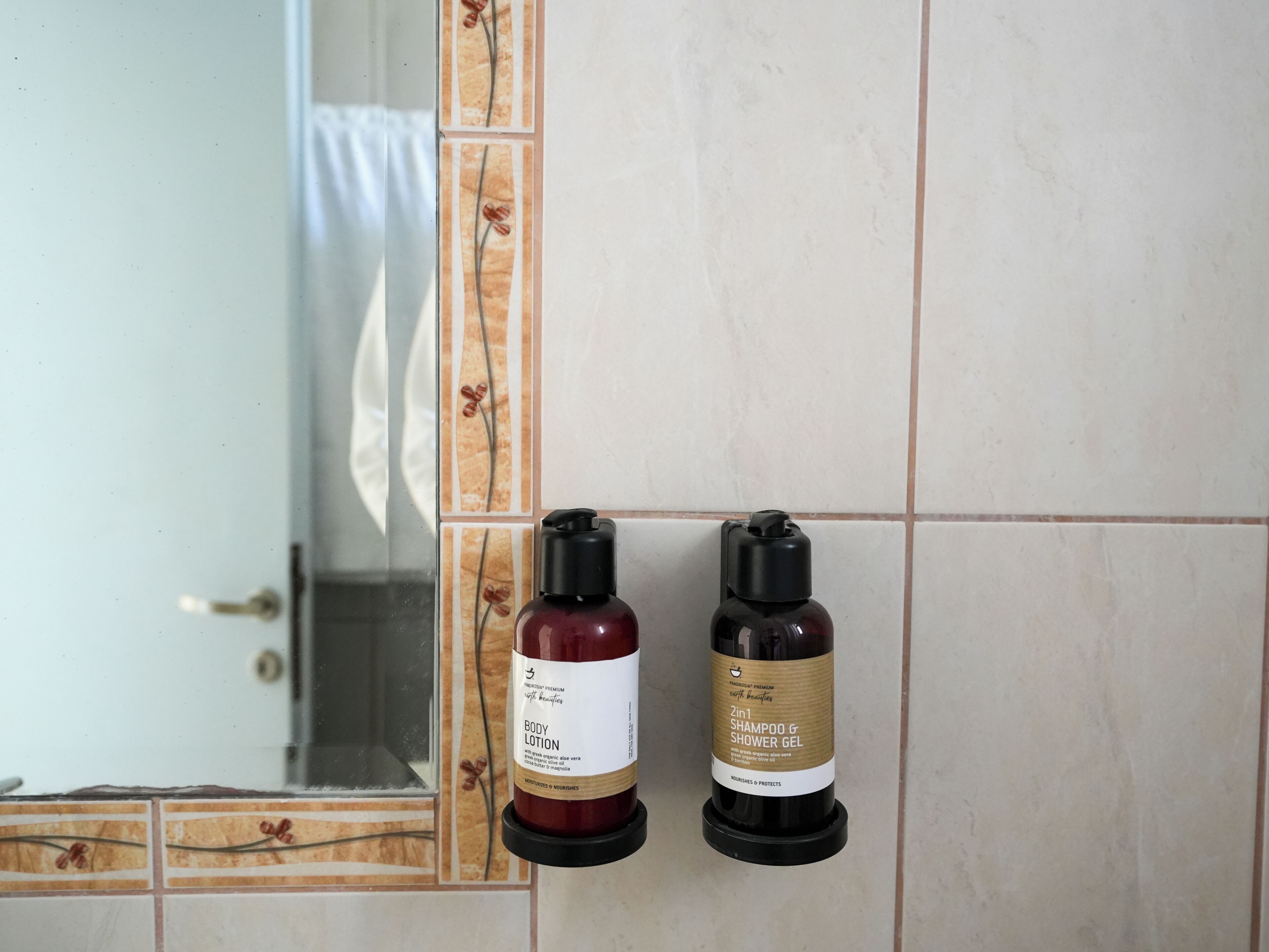 Deux flacons de lotion pour le corps et de gel douche sont posés sur un mur carrelé.