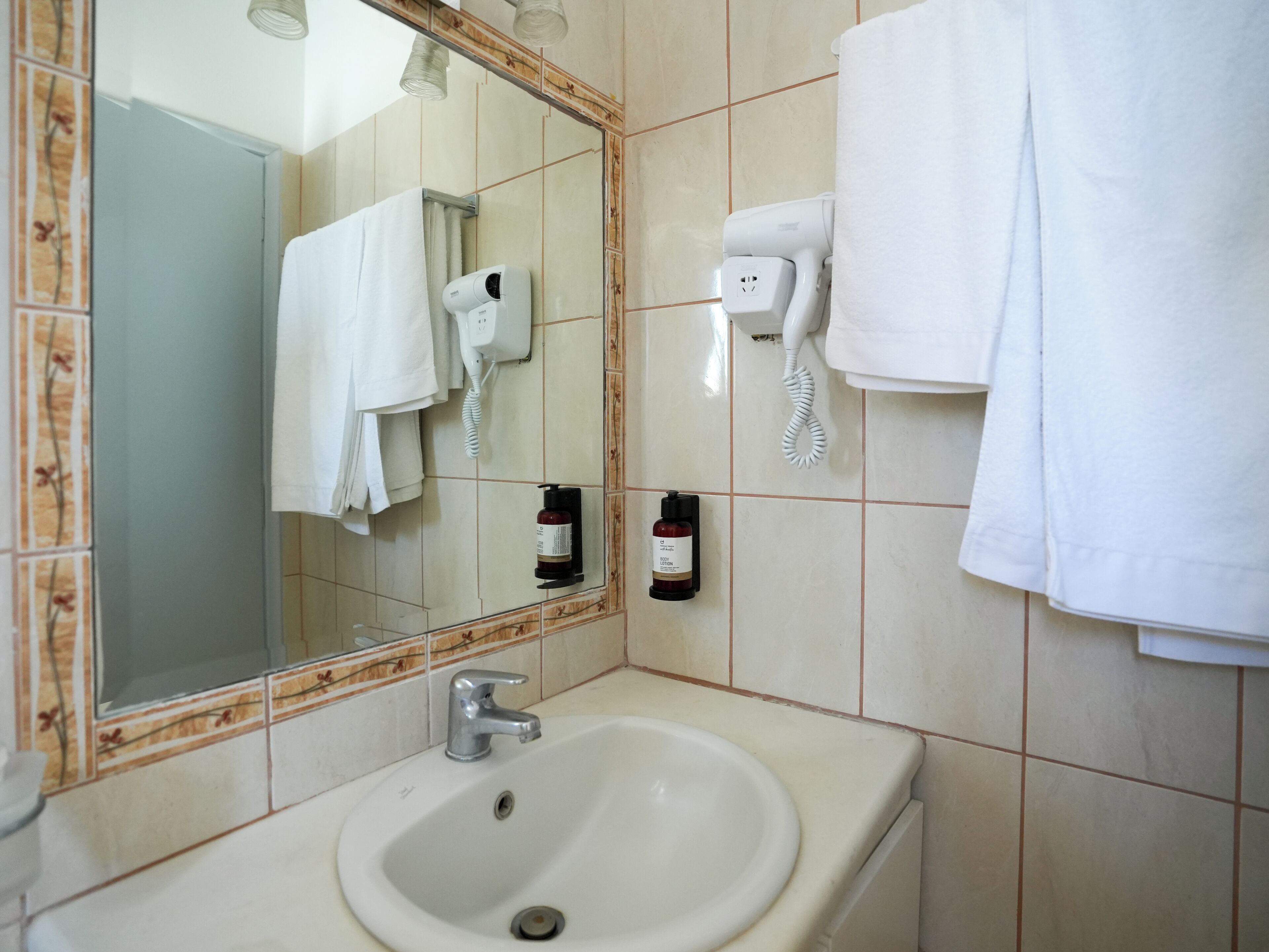 A bathroom with a sink, a mirror, a hairdryer, and a towel rack.