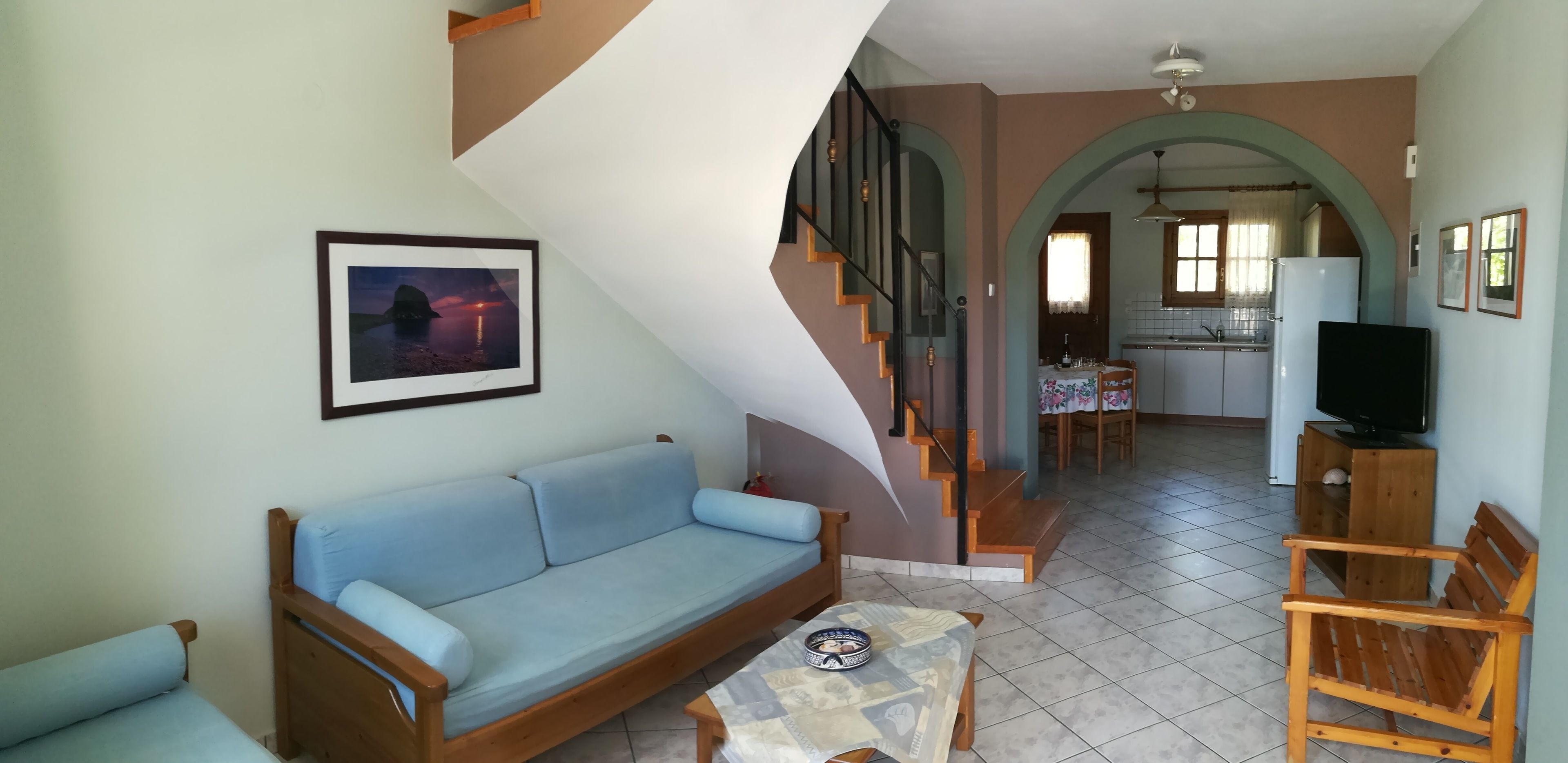 Ein Wohnzimmer mit einer Couch, einem Couchtisch und einer Treppe, die in einen Küchenbereich führt.