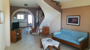 A living room with a sofa, a coffee table, and a TV stand. There is a staircase leading to another room.