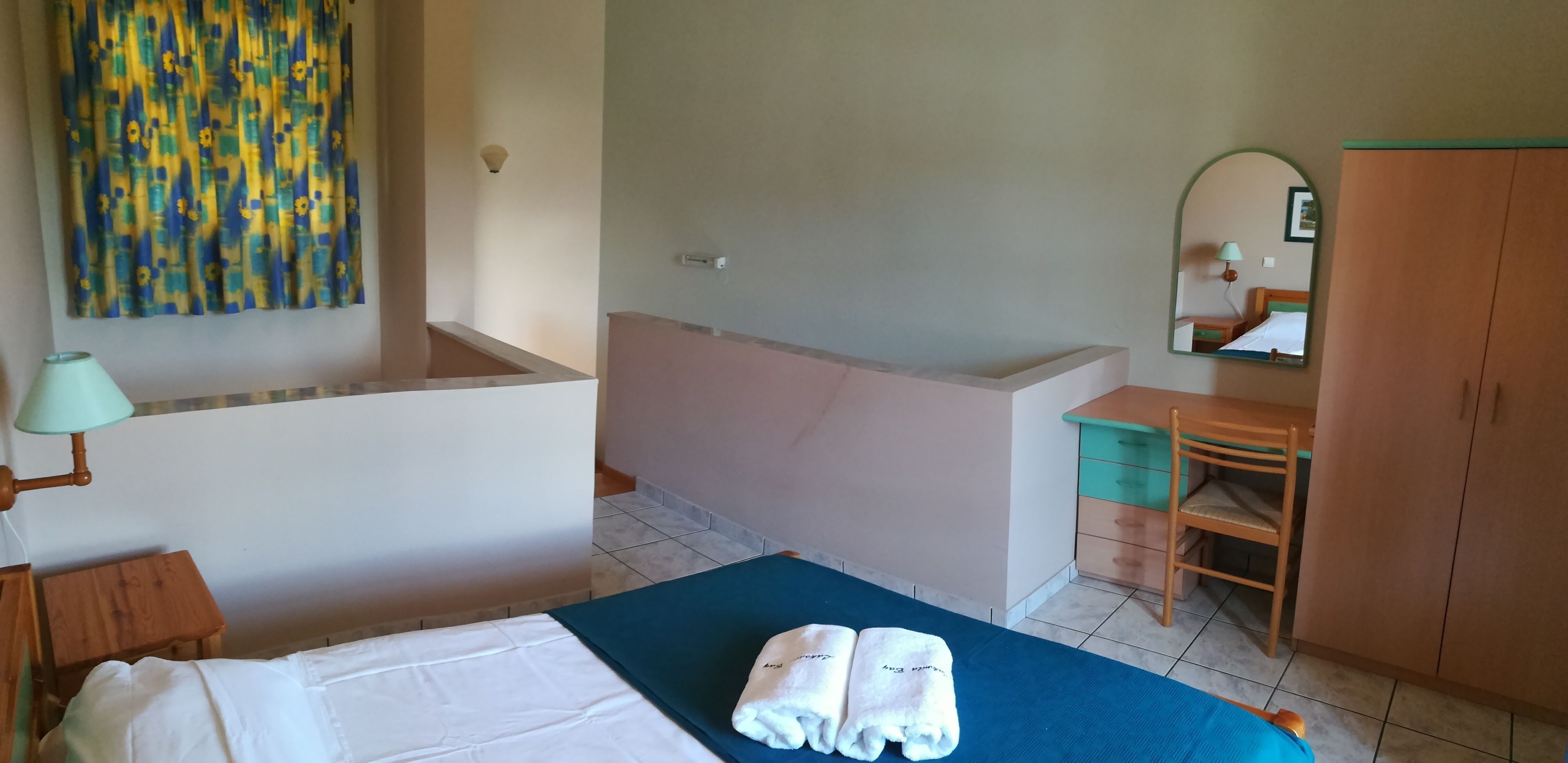 A hotel room with a bed, a bathroom, a desk, and a wardrobe.