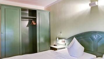 A hotel room with a bed, a nightstand, a lamp, a wardrobe, and a closet.