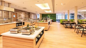 A modern kitchen with a buffet setup, wooden countertops, and a green wall in the background. - Familienresort Usedom (Trassenheide)