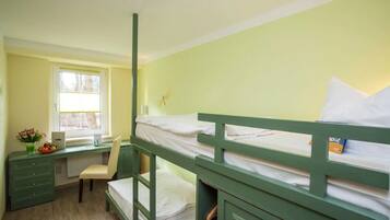 A bunk bed room with a desk and chair, a radiator, and a window with curtains.