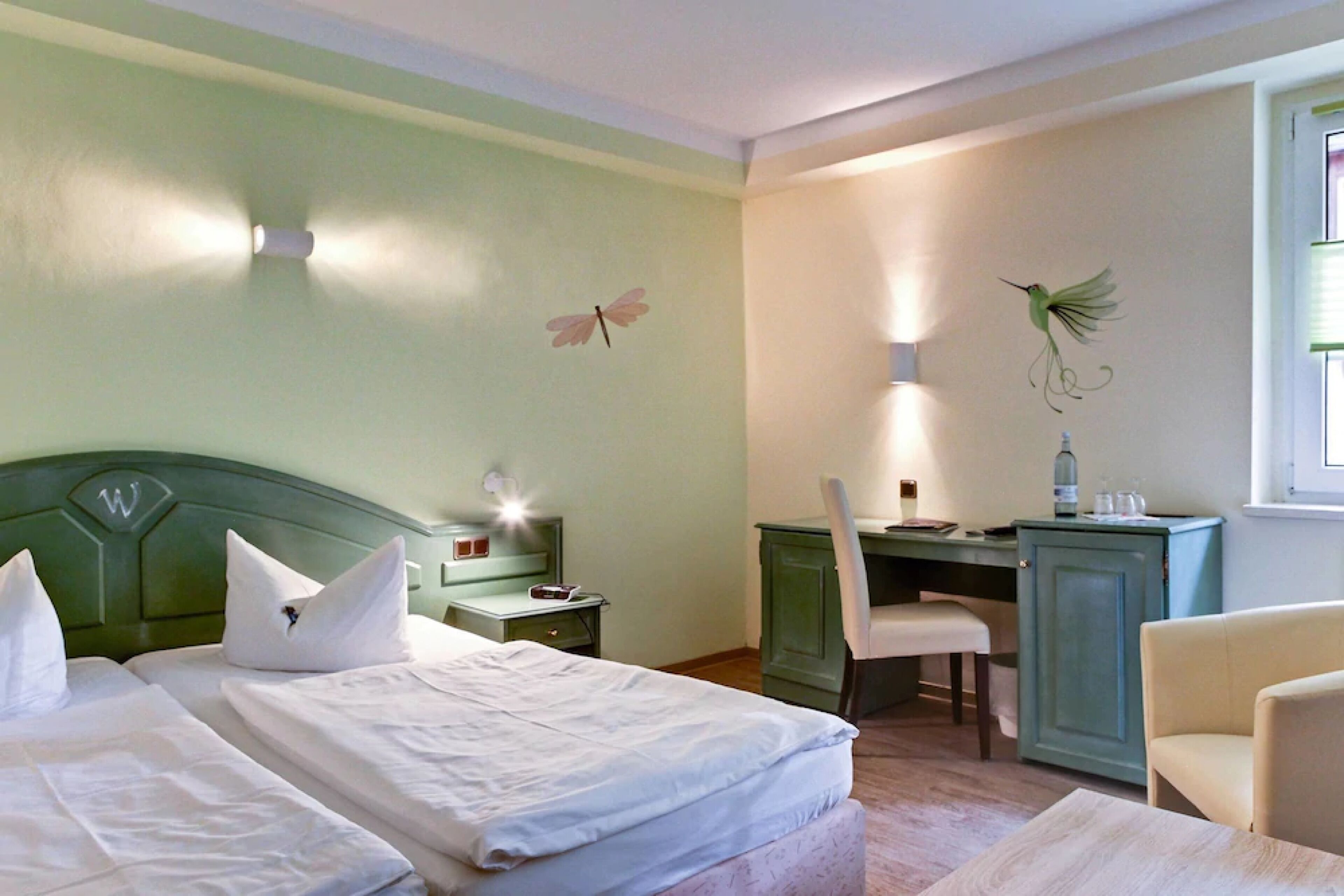 Habitación de hotel con dos camas, un escritorio, una silla y un armario.
