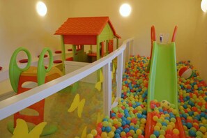 A play area with a ball pit, a small house, and a slide.