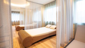A modern bedroom with a large bed, a smaller sofa, and a daybed. - Familienresort Usedom (Trassenheide)