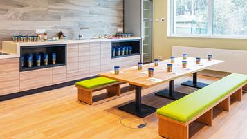 Una cocina moderna con armarios de madera, un refrigerador y una zona de comedor con bancos y una mesa.