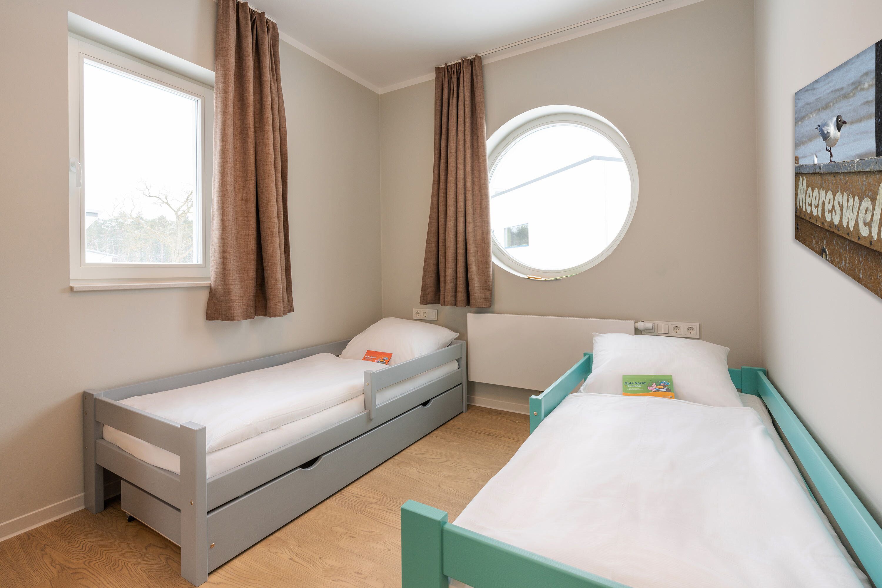 Un dormitorio con dos camas individuales, una ventana y un tragaluz redondo.