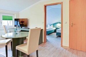 A hotel room with a dining area, a TV, a bed, and a wooden door.