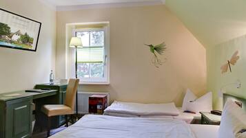 A hotel room with two beds, a desk, a chair, a window with blinds, a radiator, and a wall-mounted lamp.