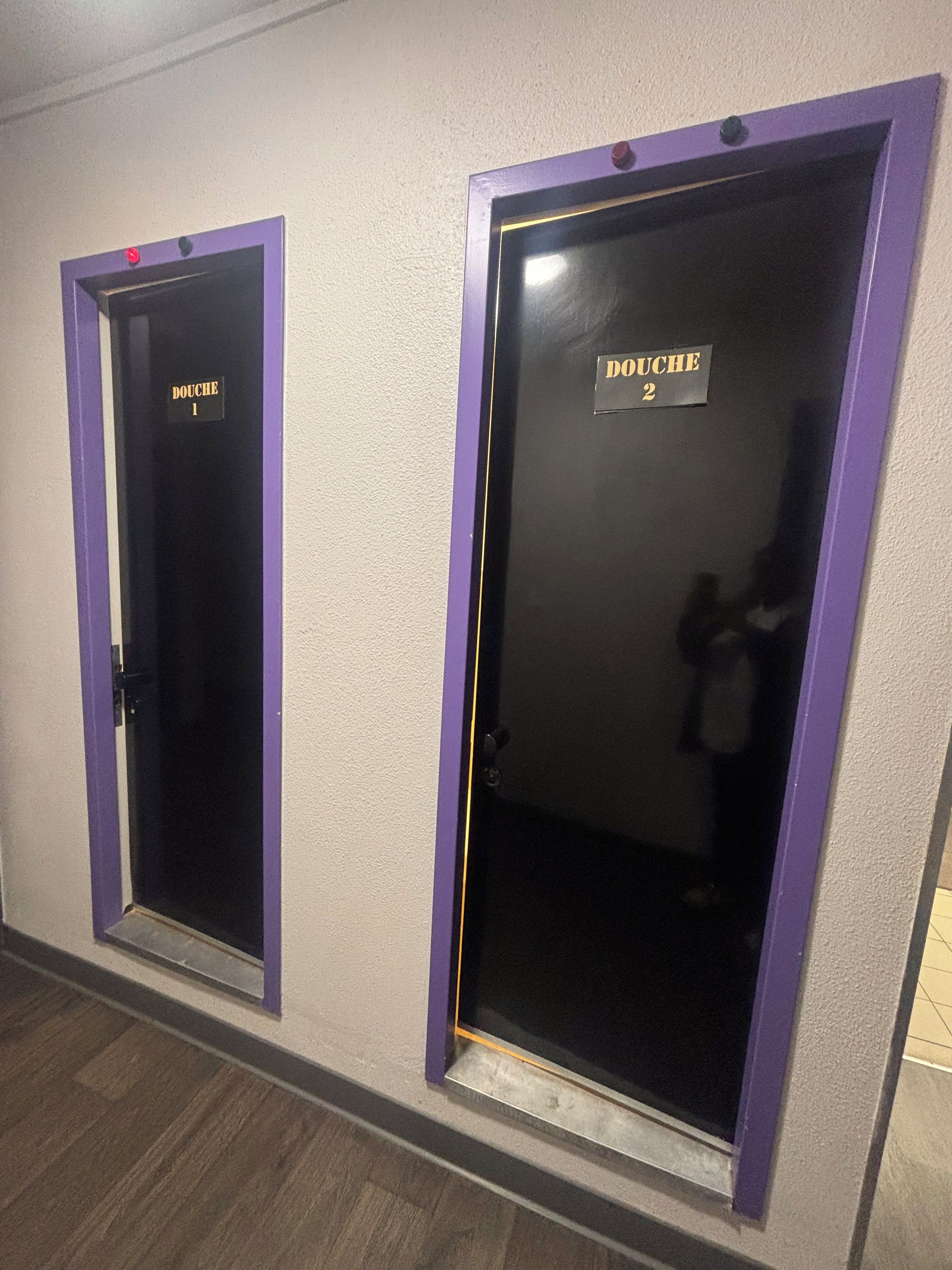 Duas portas com etiquetas 'DOUCHE', uma marcada com o número 1 e a outra com o número 2, indicando quartos separados.