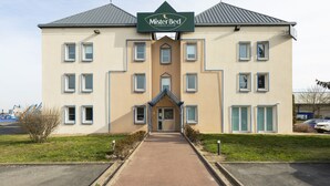 Un bâtiment à deux étages, avec une enseigne indiquant « Mister Bed » à l’entrée.
