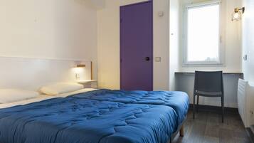 A bedroom with a bed, a desk, a chair, a purple door, and a window.