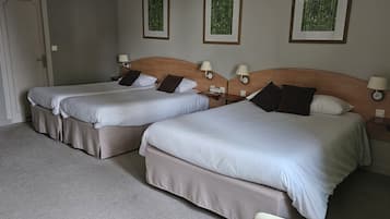 A hotel room with two beds, each with a wooden headboard, bedside lamps, and a small table.