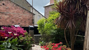 A stone-paved courtyard with a brick building, a wooden door, and various plants. - Hotel le Broceliande, Sure Hotel Collection by Best Western (Bedee)