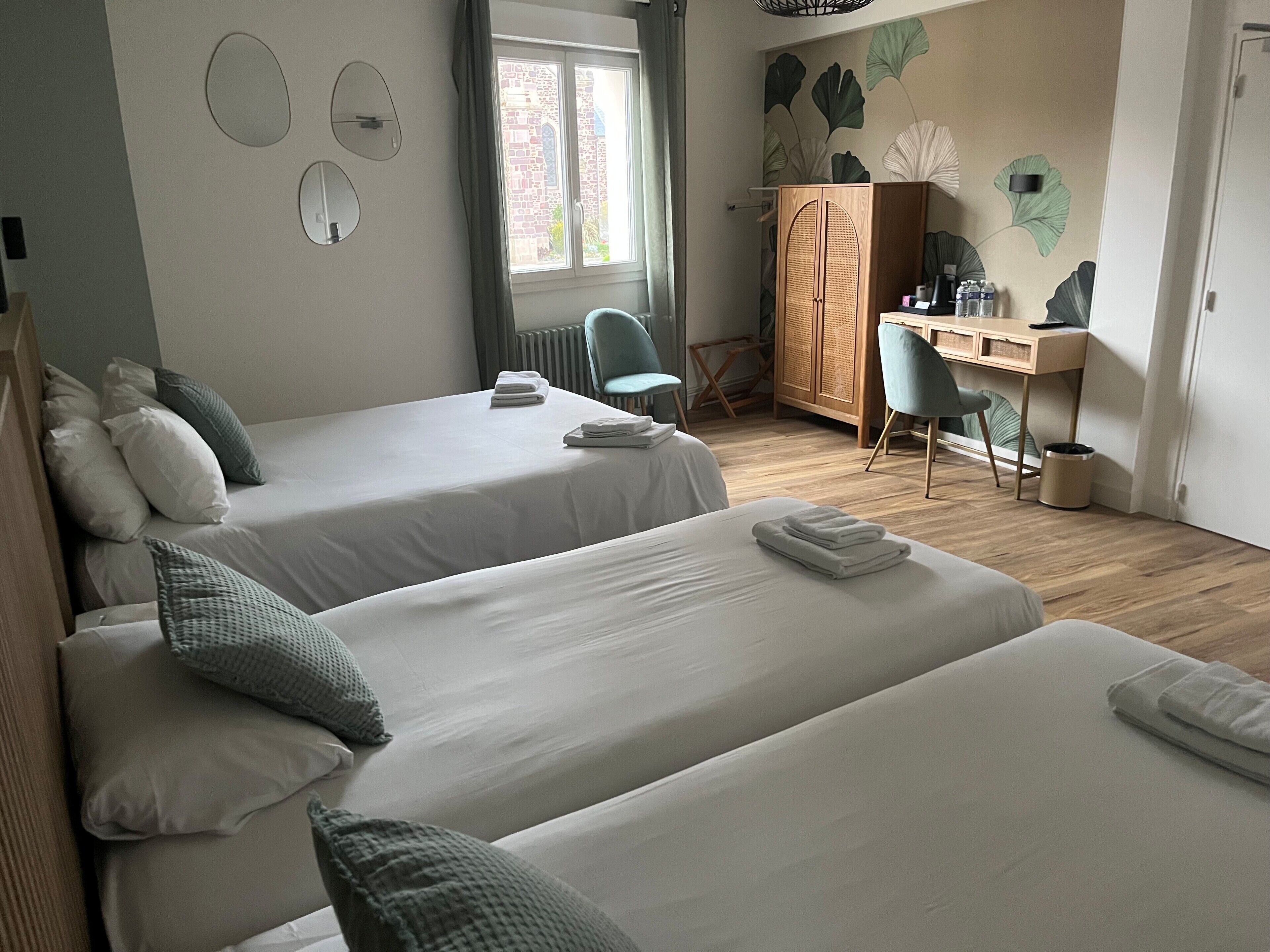 Habitación de hotel con dos camas, un escritorio, una silla y un radiador.