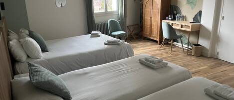 Habitación de hotel con dos camas, un escritorio, una silla y un radiador.