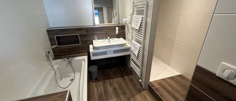 A modern bathroom with a bathtub, a sink, a mirror, and a towel rack.