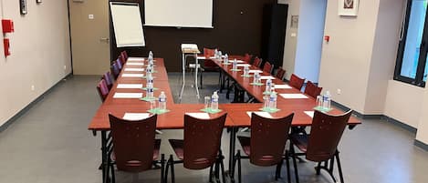 A conference room with a long table, chairs, water bottles, and a whiteboard.