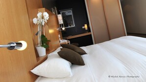 A modern hotel room with a bed, white pillows, a wooden wardrobe, and a potted orchid. - Hotel le Broceliande, Sure Hotel Collection by Best Western (Bedee)