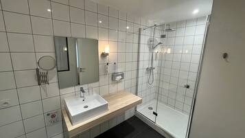 A modern bathroom with a white sink, mirror, and shower.