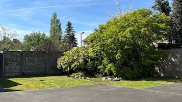 A parking lot with a clear sky, a grassy area, and a variety of trees.