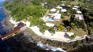 An aerial view of a coastal resort with a beach, a pool, and several bungalow-style accommodations. - Island Magic Resort (Mele)