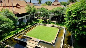A traditional building with a tiled roof, surrounded by lush greenery and a central water feature.