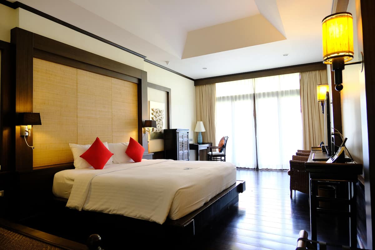 A hotel room with a large bed, a desk, and a chair.