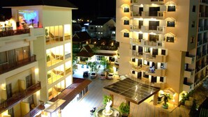 Un hôtel à plusieurs étages doté de balcons, d’un jardin sur le toit et d’une installation de panneaux solaires.