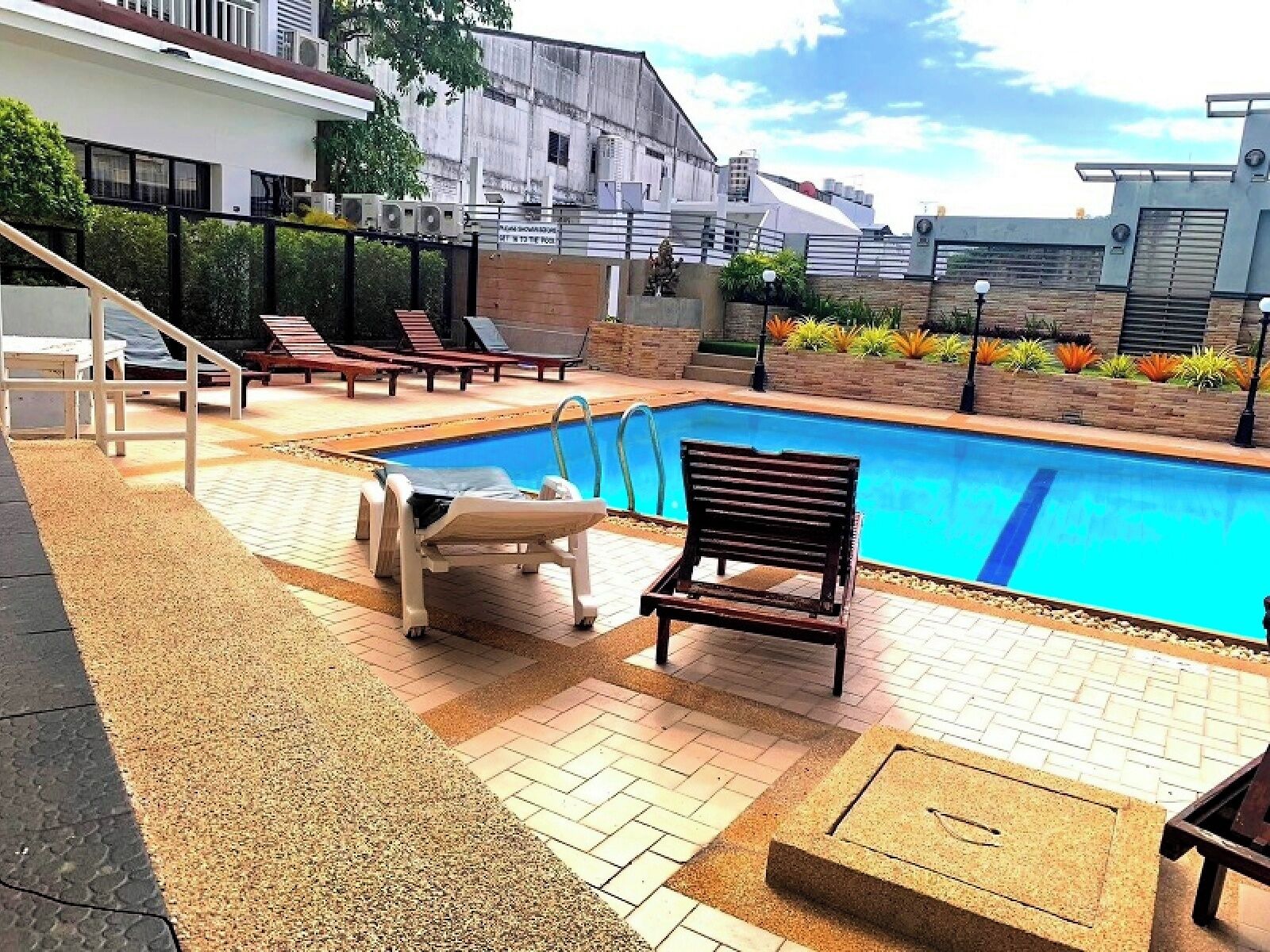 A swimming pool with lounge chairs and a small deck area.