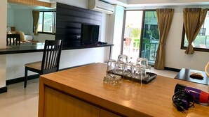 Une cuisine moderne avec un plan de travail noir, une table à manger avec des chaises et un téléviseur fixé au mur.