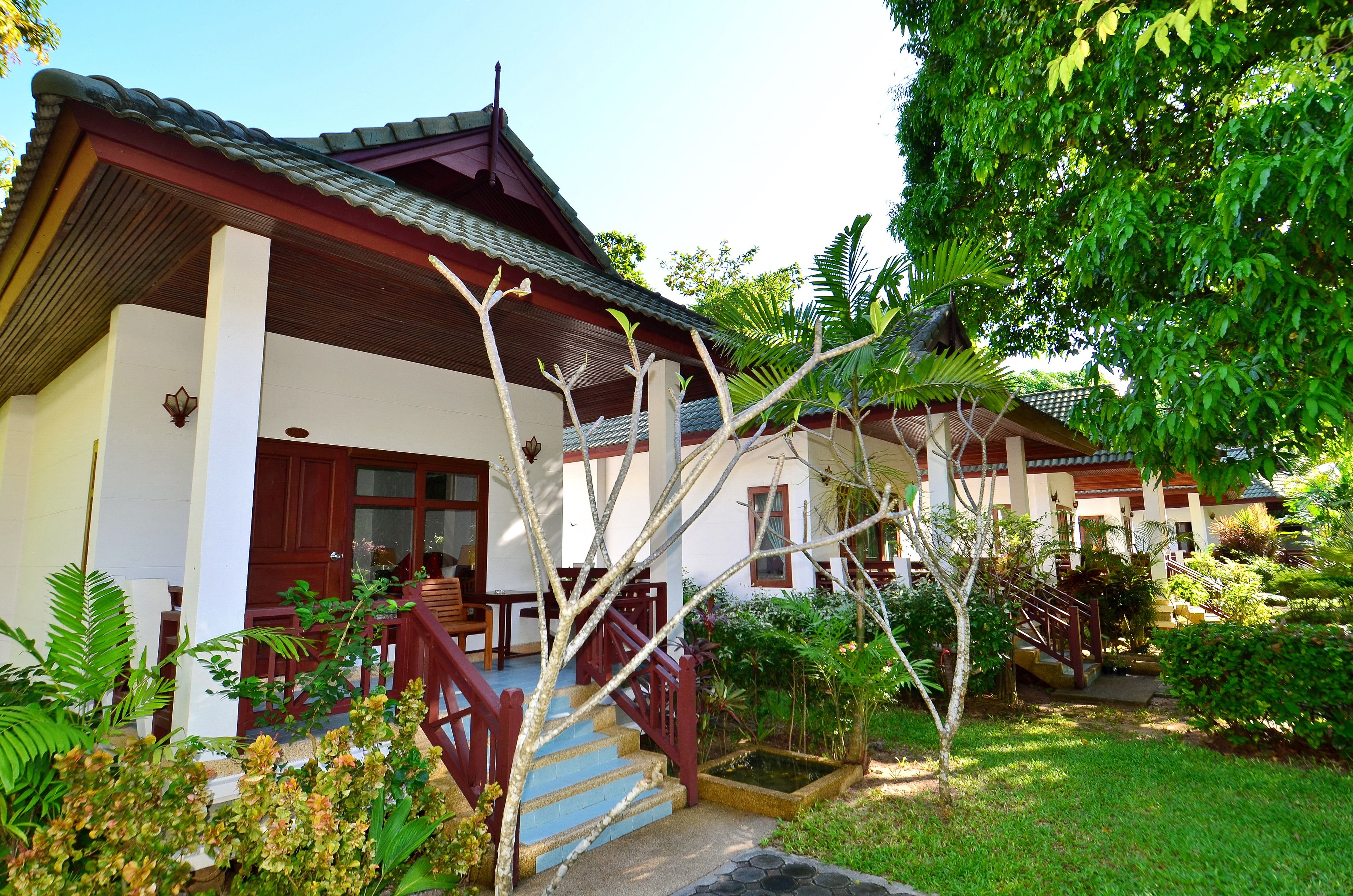 A traditional-style building with a staircase leading to a wooden deck, surrounded by lush greenery.