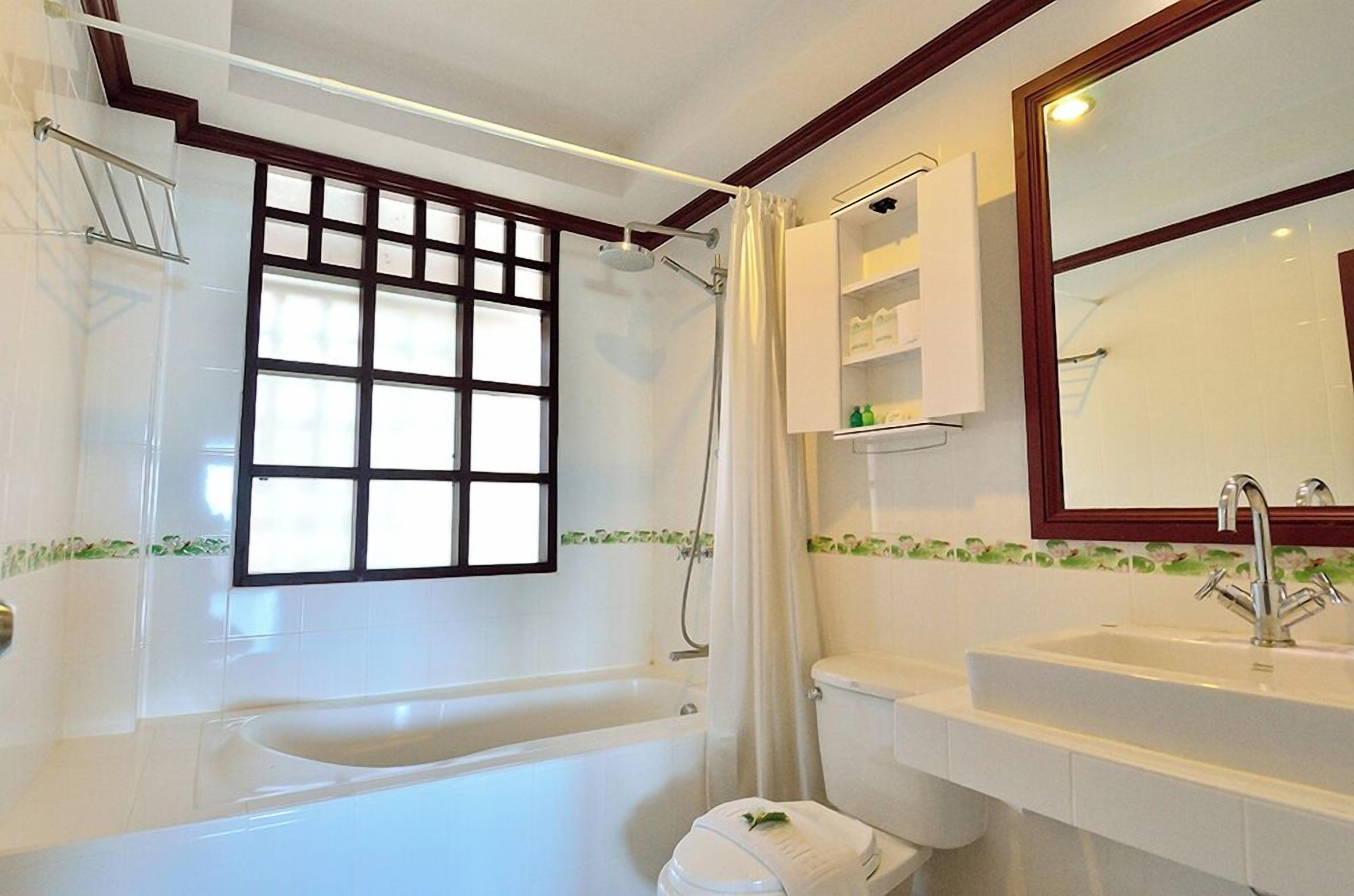 Une salle de bain avec une baignoire, des toilettes, un lavabo et un grand miroir.