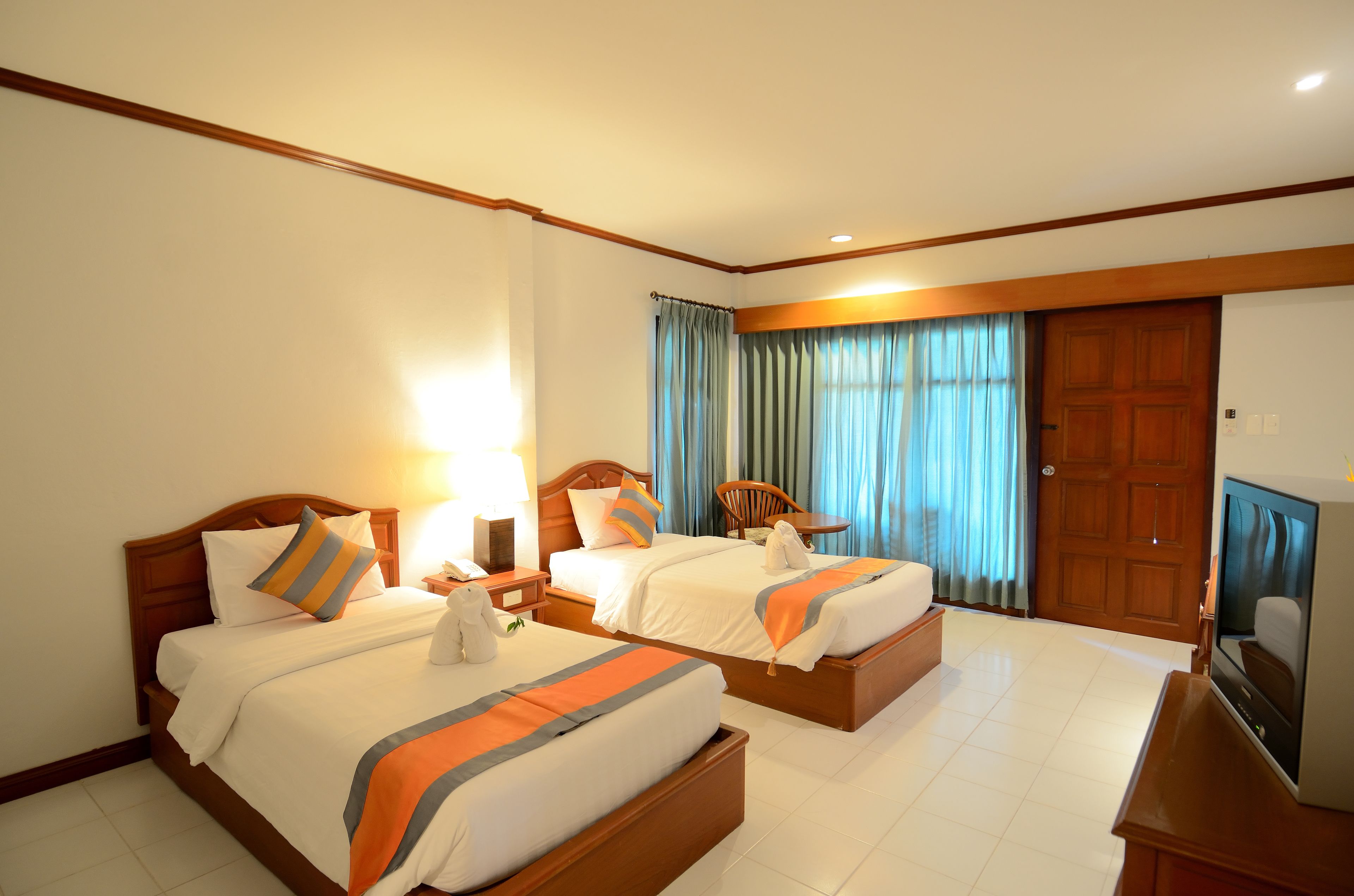 A hotel room with two beds, a TV, and a wooden door.
