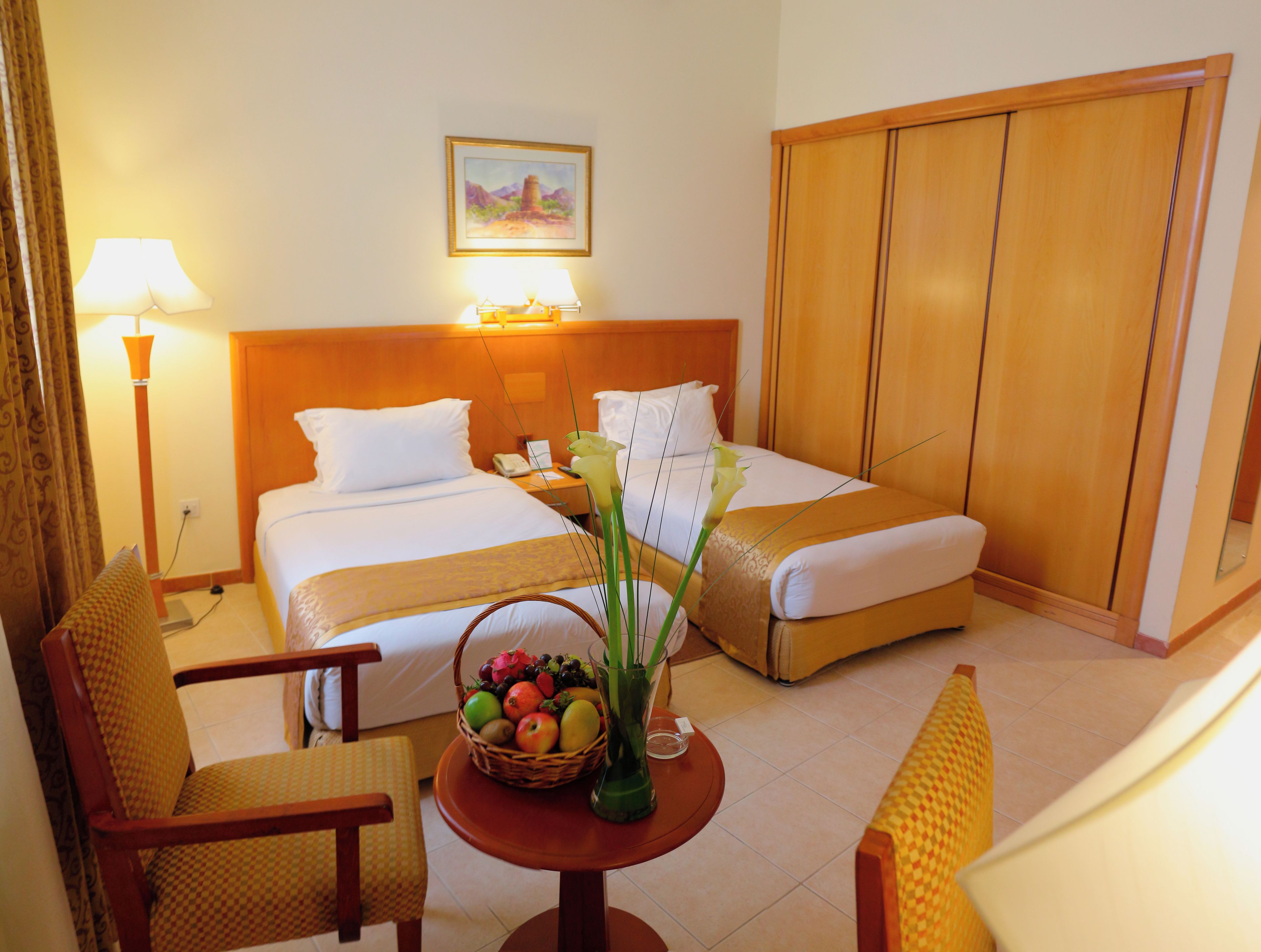 A hotel room with two beds, a sitting area with a table, and a wardrobe.