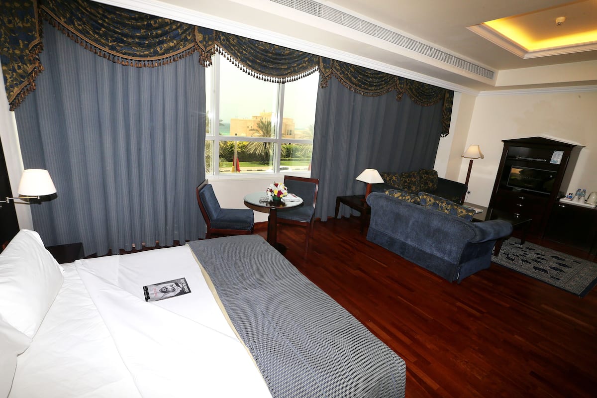 Ein Hotelzimmer mit Bett, Sofa, kleinem Tisch mit Lampe und Fernseher.