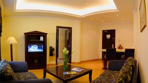Ein Wohnzimmer mit Fernseher, einer Couch, einem Couchtisch und einem Essbereich mit Stühlen und einem Tisch.