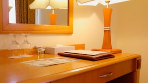 Ein Holztisch mit einem Spiegel, einer Lampe, einer Taschentuchbox, einem Notizbuch und zwei Gläsern.