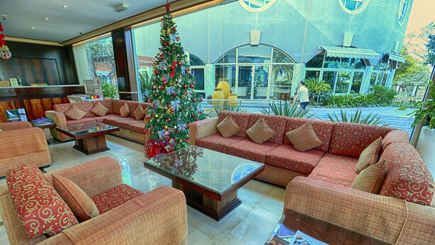 Eine Lobby mit roten, gemusterten Sofas, einem Glastisch und einem Weihnachtsbaum.